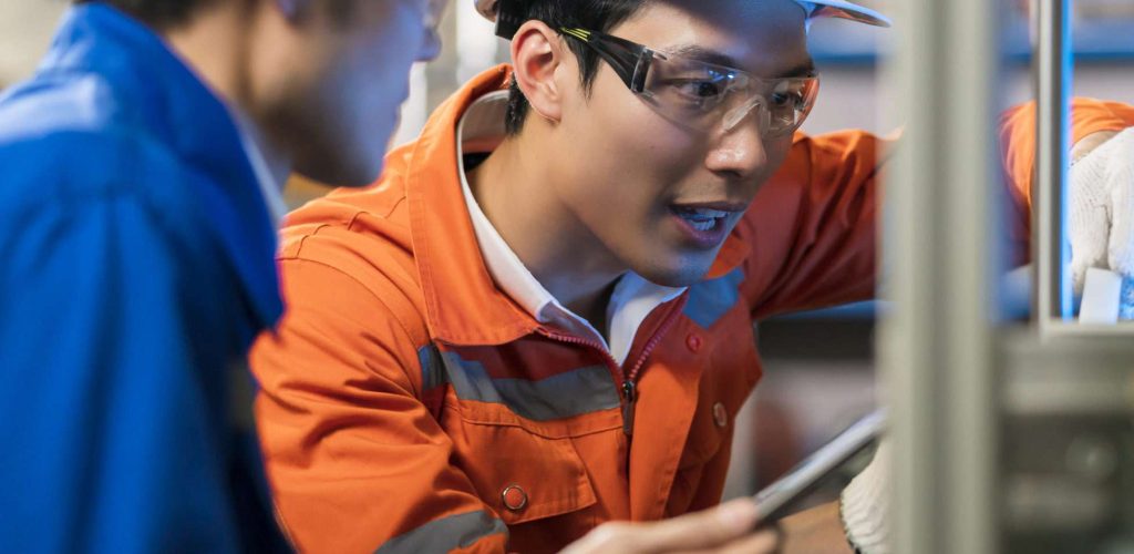 Male Asian engineer professional  having a discussion standing by the machine in the factory ,two asian coworker brainstorm explaining and solves the process curcuit mother board of the machine