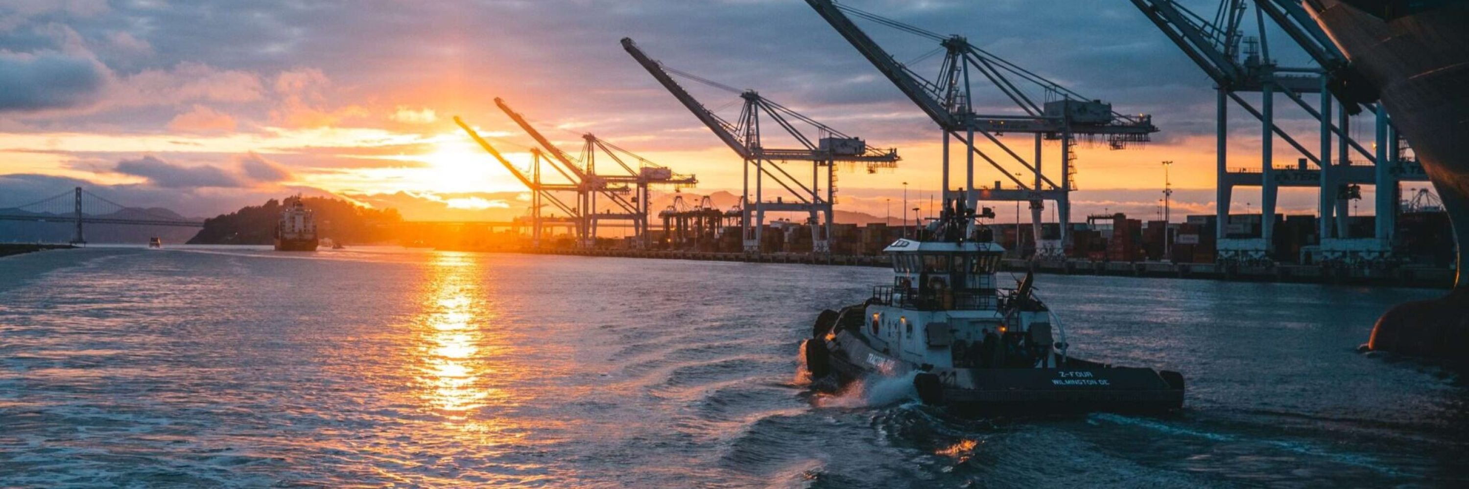 a panoramic shot of oil rigs at sea with a beautiful sunset in the background, under cloudy sky