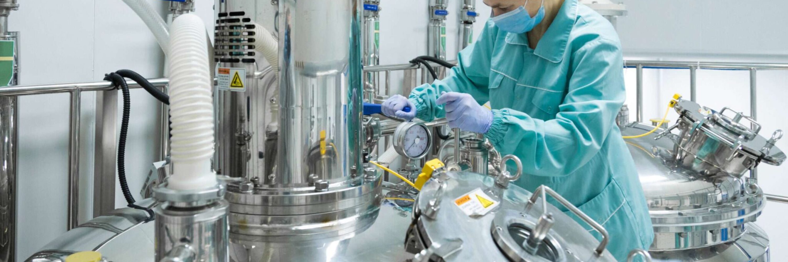Pharmaceutical factory woman worker in protective clothing operating production line in sterile environment Pharmaceutical technician in sterile environment at pharmacy industry